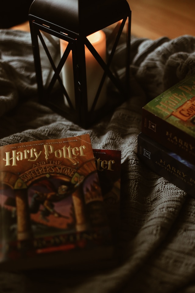 Copies of the Harry Potter books beside a lamp with a lit candle inside.