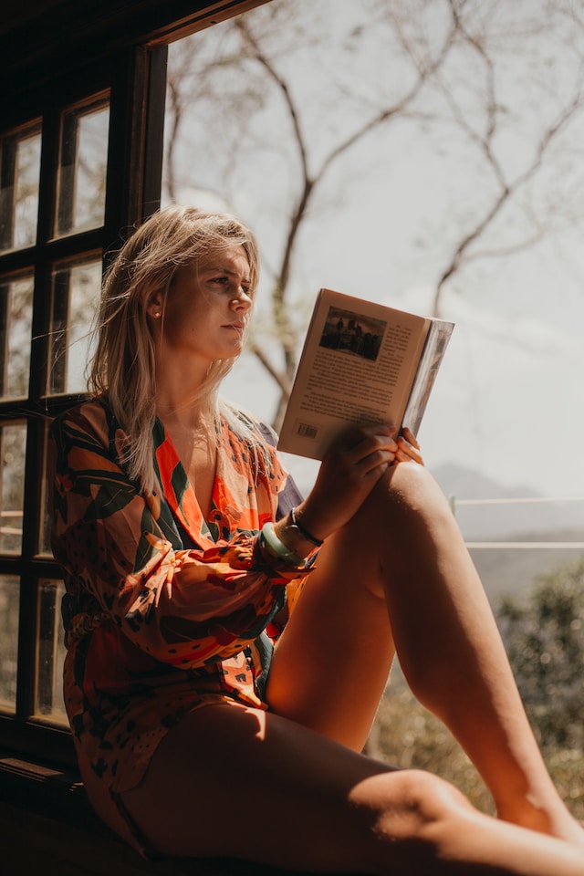 A woman holding a book, looking at the distance.