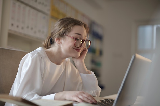 A woman in glasses using a laptop.