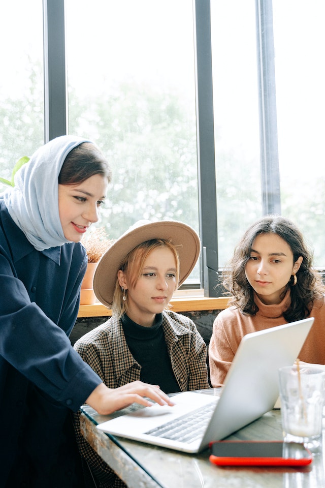 Three women looking at a laptop screen.