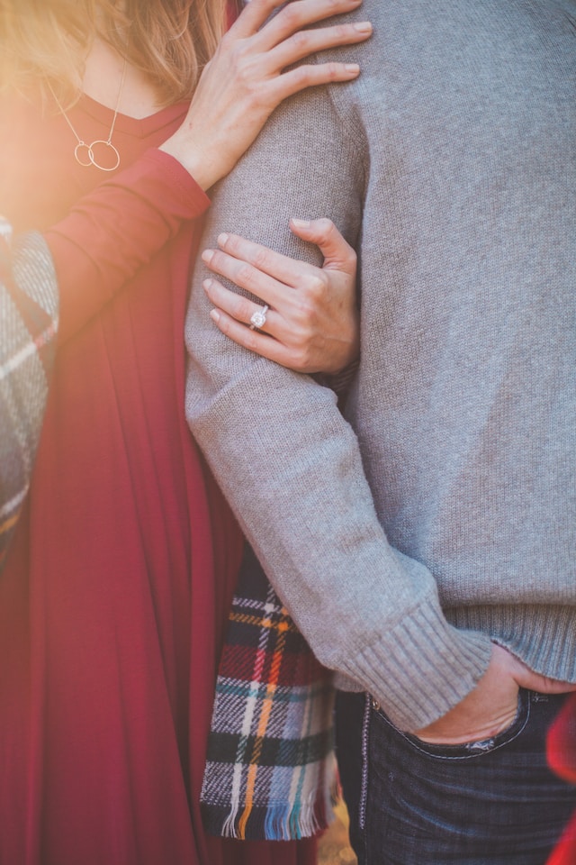 A woman's hands clasping the arm of the guy standing beside her