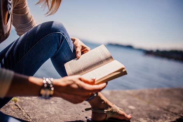 A woman reading a book on the side of a lake