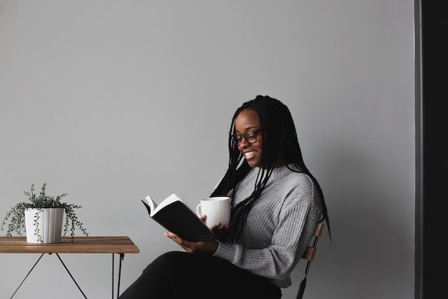 Woman reading a book while holding a cup of coffee