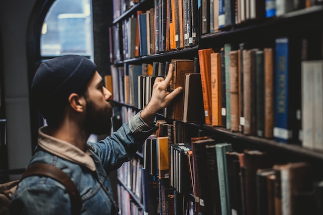 A guy returning a book on a shelf