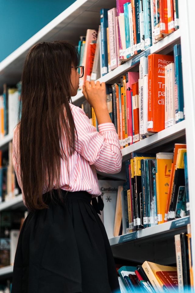 Girl checking out the lineup of books on a shelf