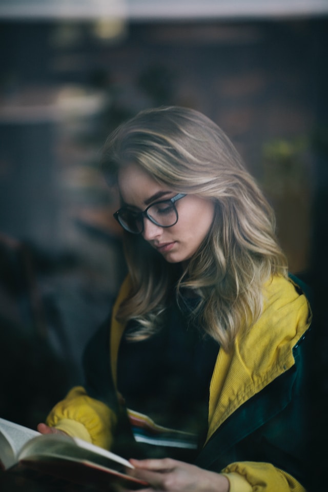 Woman in glasses with an open book on her lap