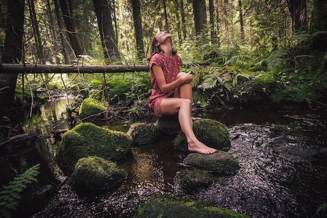 Woman sitting on a moss-covered rock