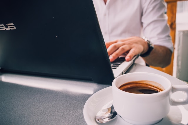 Person on a laptop with a cup of coffee on the side