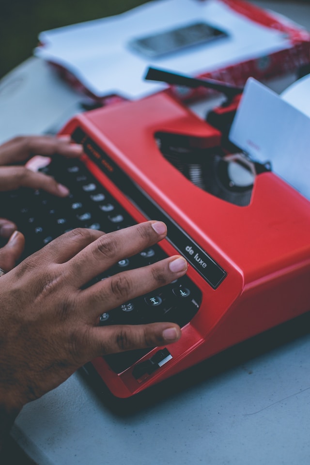 Person using a red typewriter