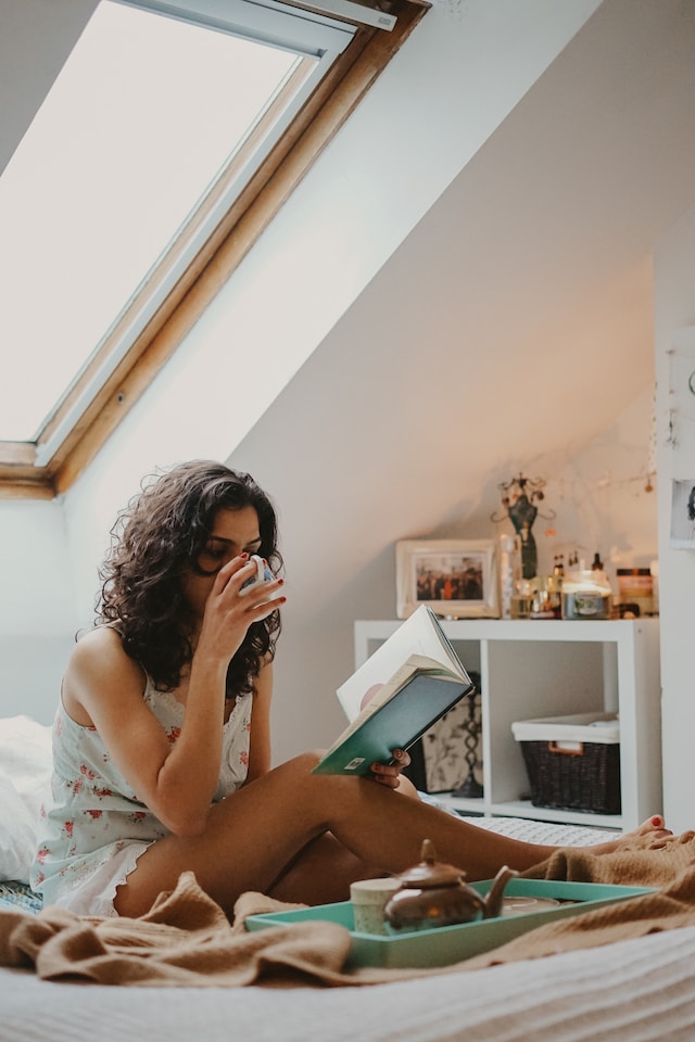 Woman drinking tea while reading a book
