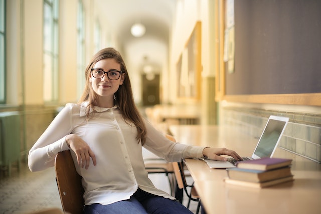 Young woman with glasses working on a desk in a hallway