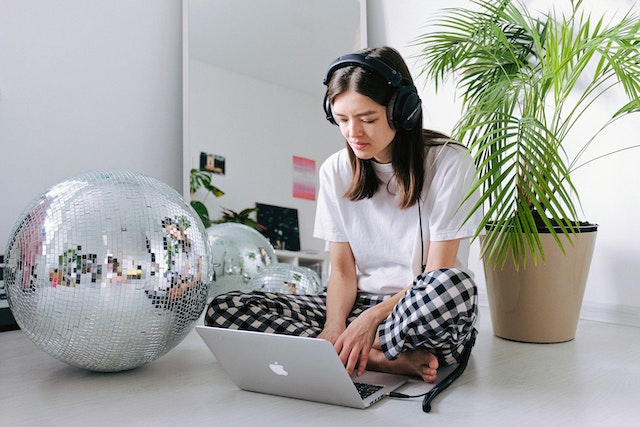 Young woman in pajamas with headphones on working from home
