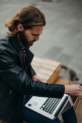 Guy holding an open laptop outdoors