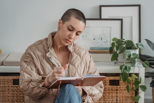 Woman in a jacket writing on a notebook