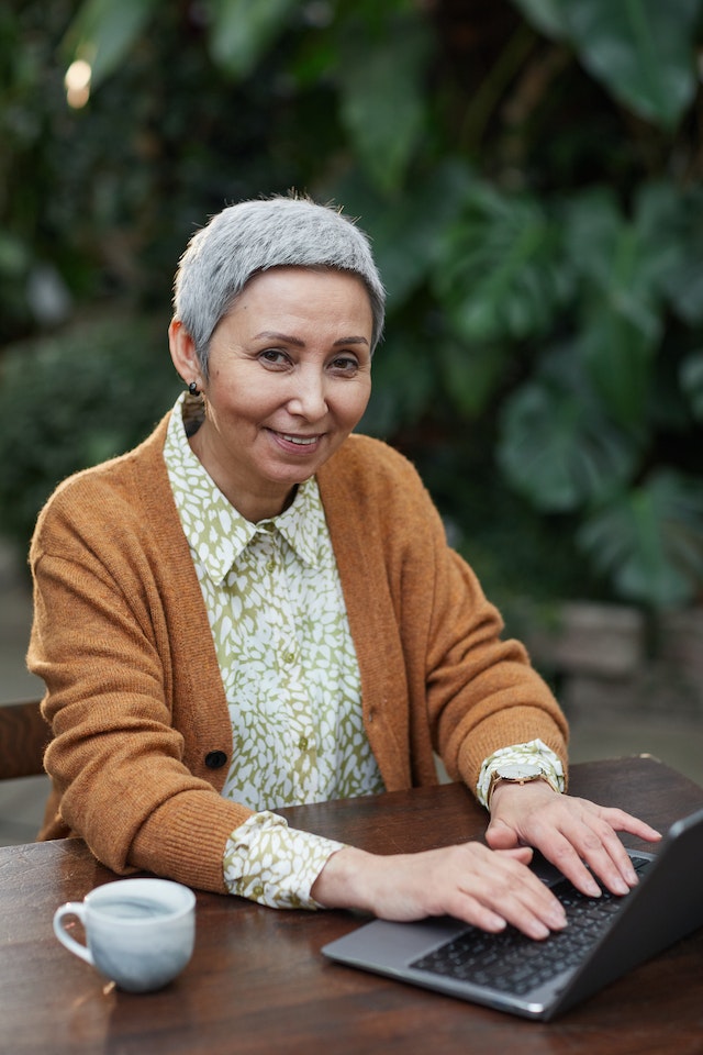 Woman working on her laptop outdoors while enjoying a cup of coffee