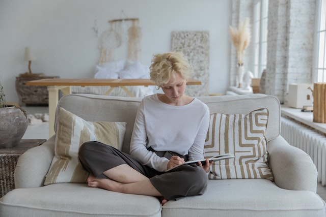 Woman sitting on the couch writing on her notepad