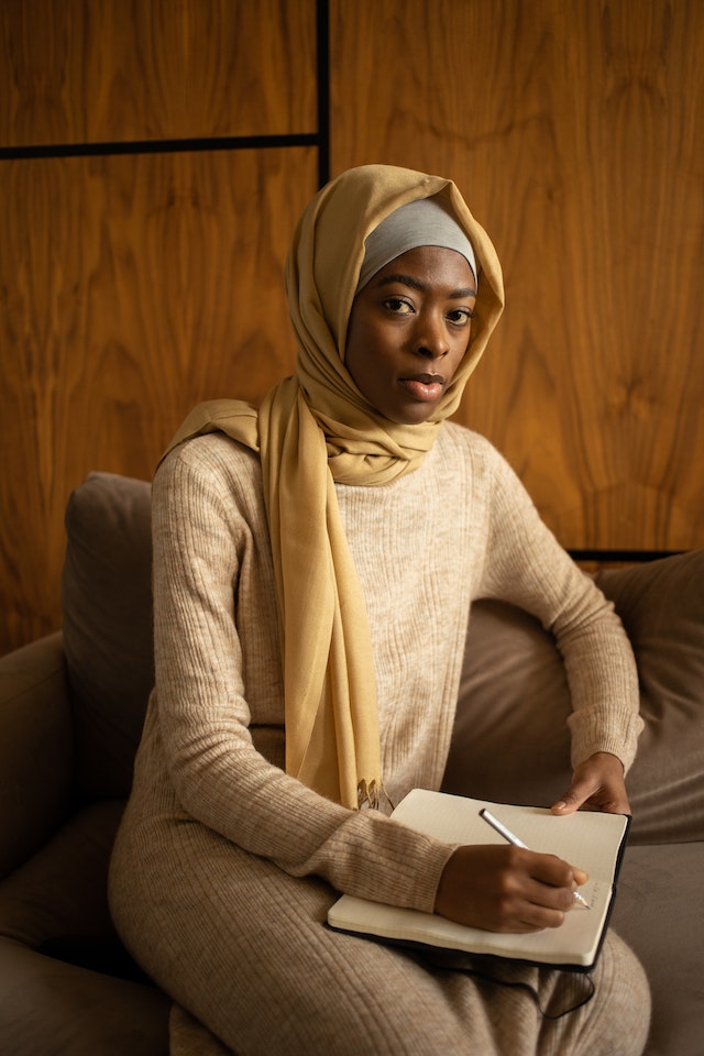 Woman sitting on the couch writing on her notebook